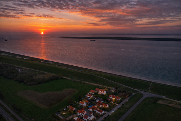 Zonsondergang boven kustdorp met schepen.png